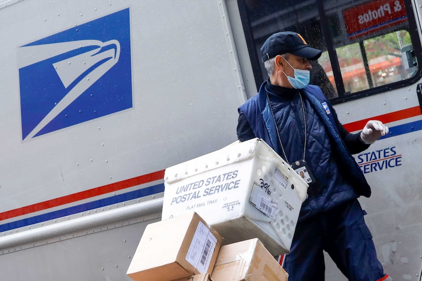 A US postal worker in a mask outside a truck