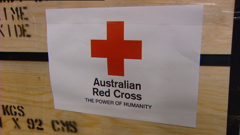 Generic TV still of Australian Red Cross logo on side of wooden cases in aid warehouse in Brisbane