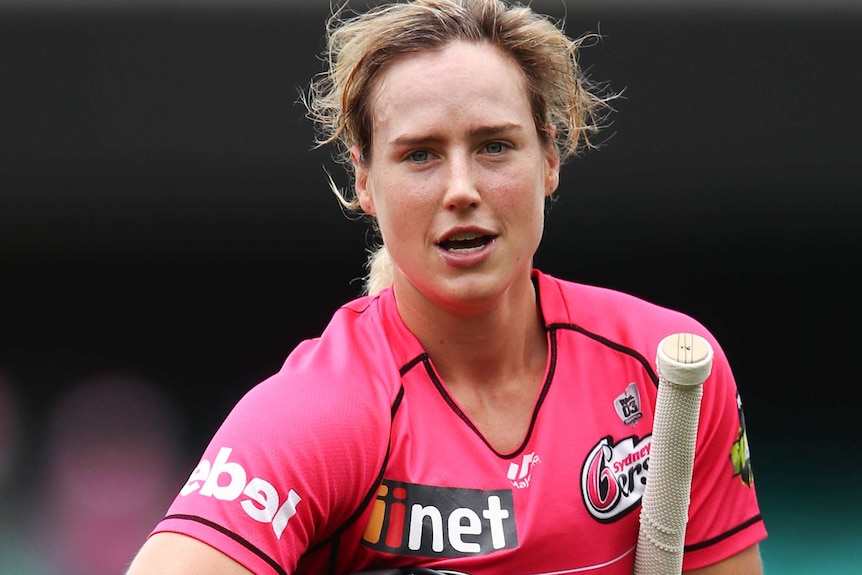 Ellyse Perry carries her bat, gloves and helmet off the field.