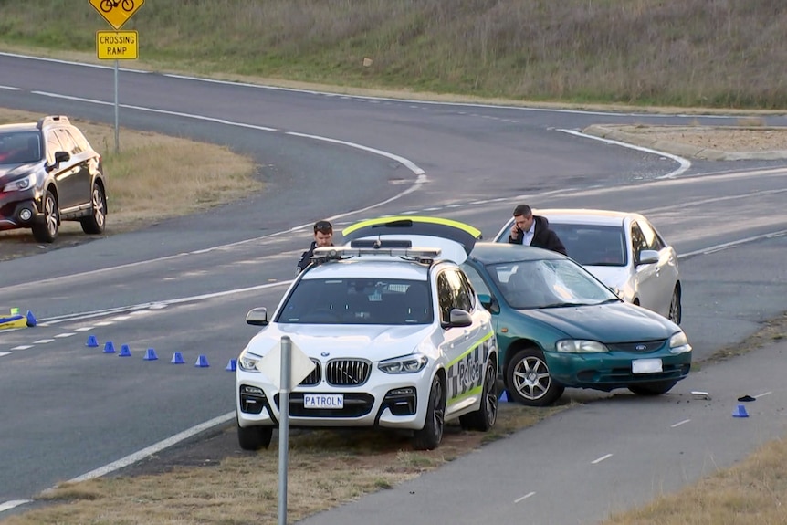 Police and police cars on the side of the road. 