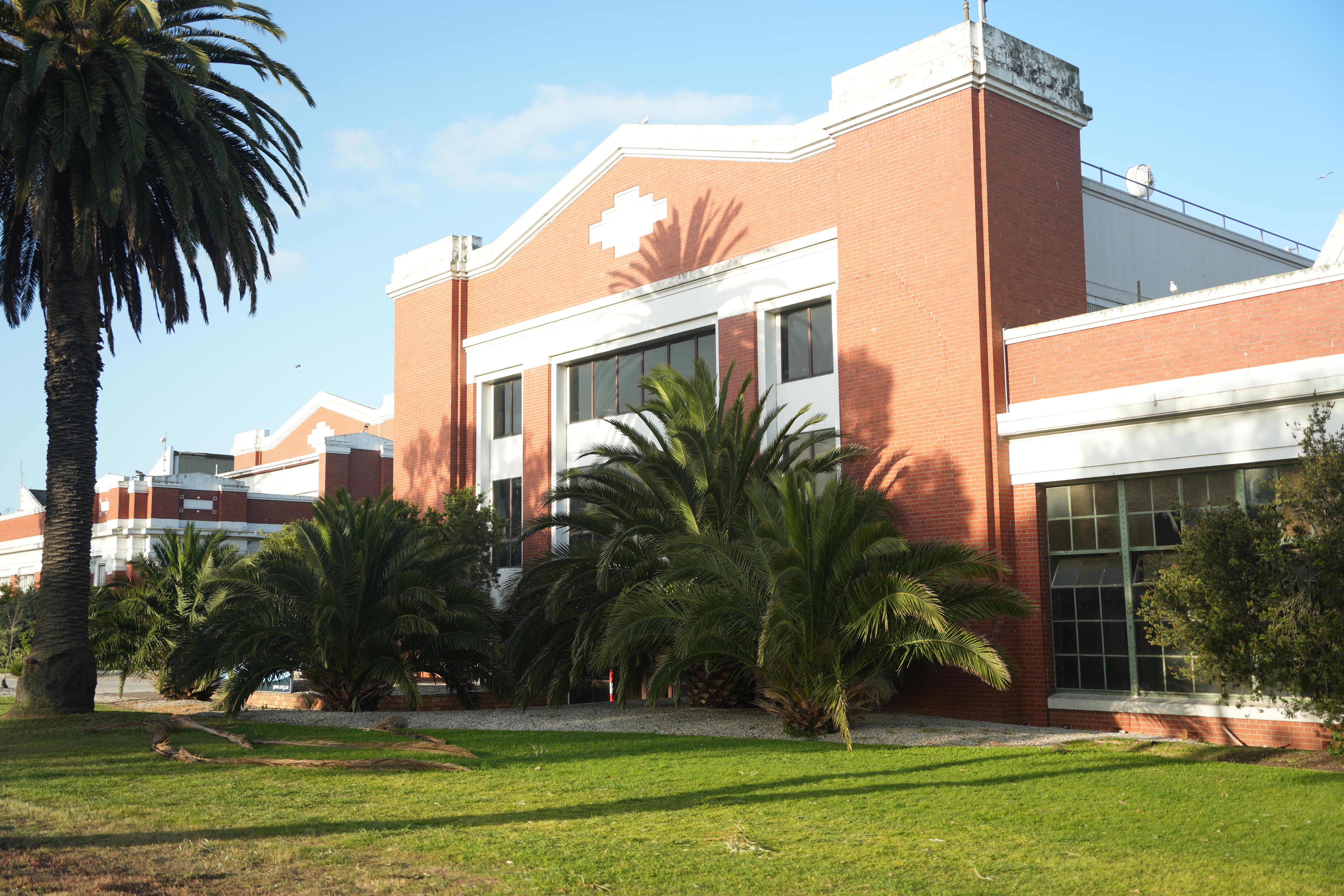 A red-brick building with white features around the windows, and a green lawn at the front.
