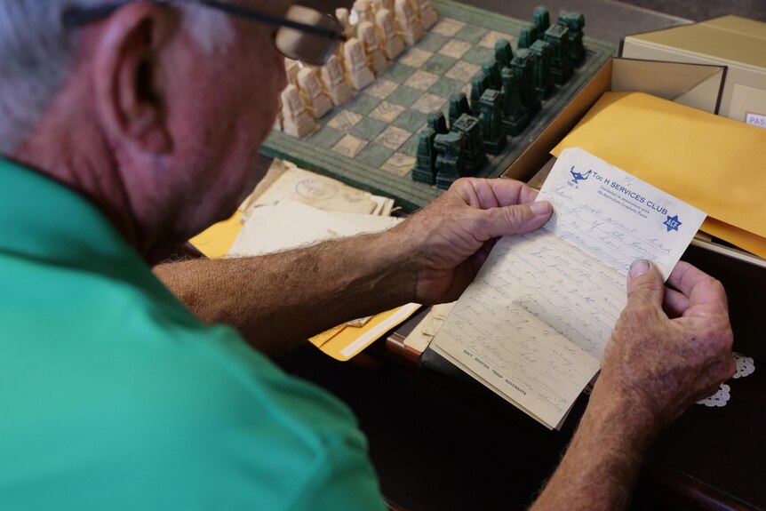 a man holds an old letter and reads it 