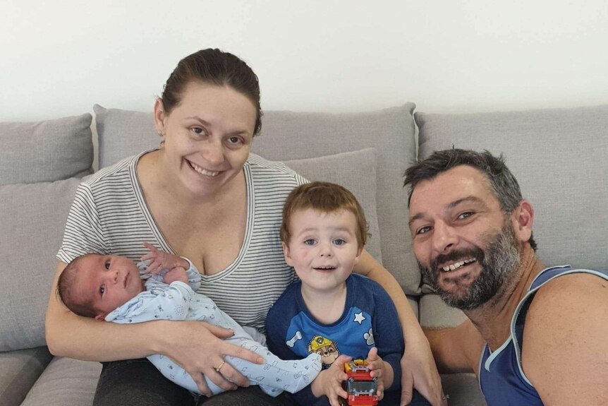 A young family huddled and smiling.