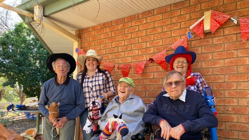 A group of older men and women with toy horses, at a nursing home, Coonamble western New South Wales