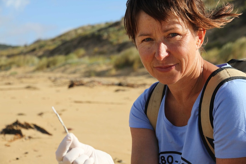 Volunteer Colleen Hughson holding a plastic pipe