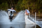 man doing wheelie on dirt bike and splashing woman with water