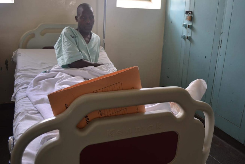 Peter Maloungu lies in a hospital bed