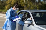 Health worker writes on paperwork with a motorist at a COVID drive-through testing site Brisbane