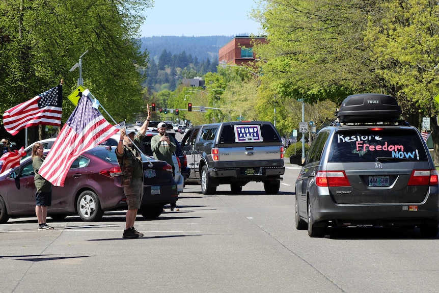 People waving American flags wave at cars in Oregon.