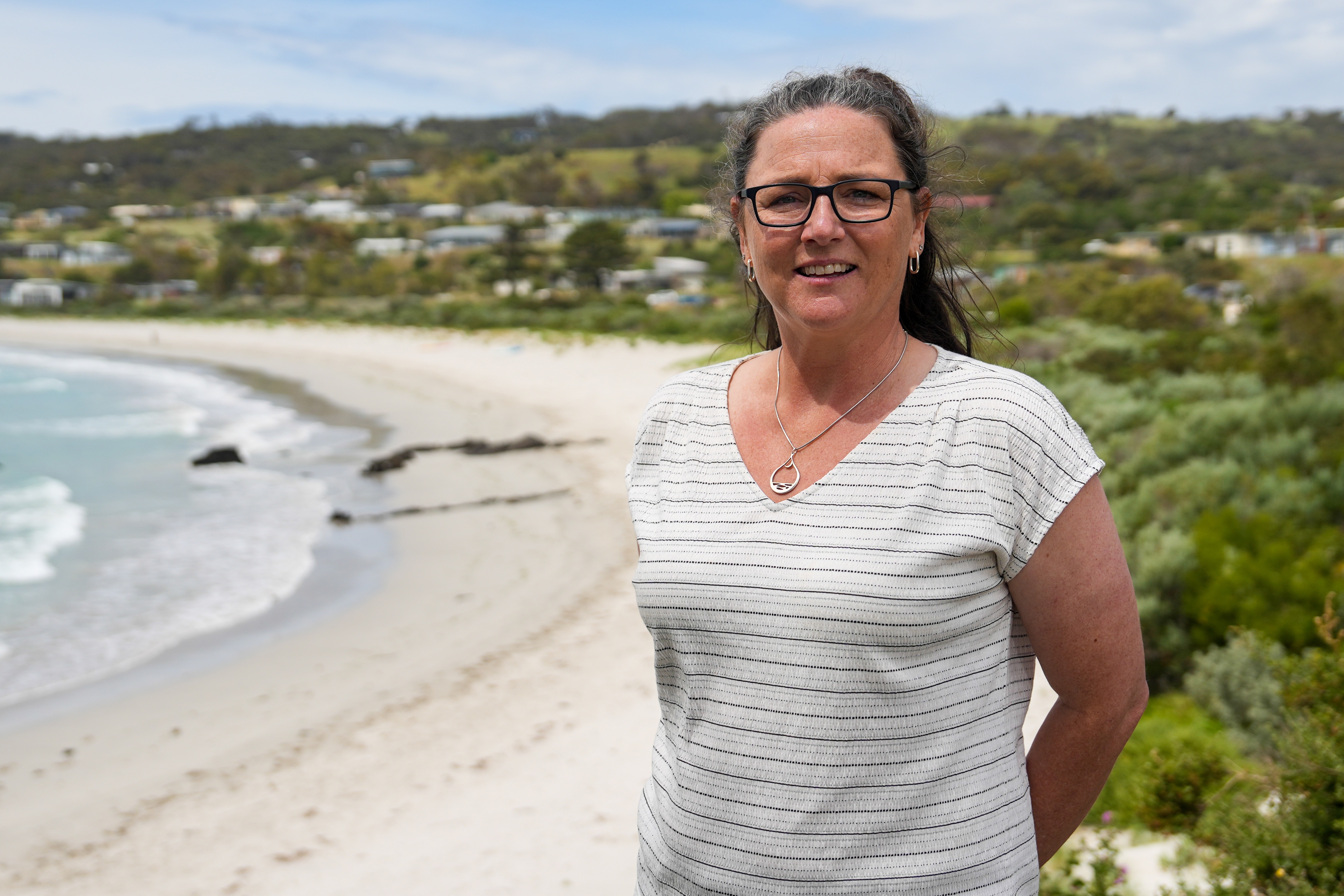 A woman is standing near a beach.