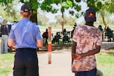 A police officer and boy attend a community meeting in Fitzroy Crossing.