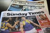 Copies of The Sunday Times and The West Australian newspapers lie on a dark table.