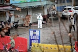 A man in a hazmat suit standing outside a Chinese marketplace