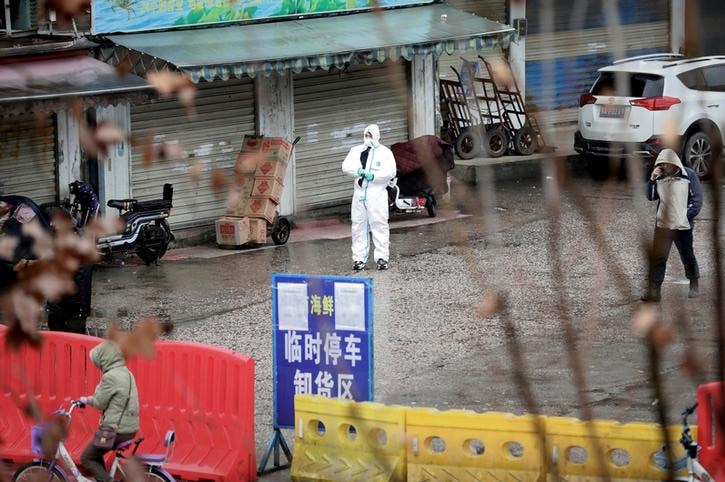 A man in a hazmat suit standing outside a Chinese marketplace