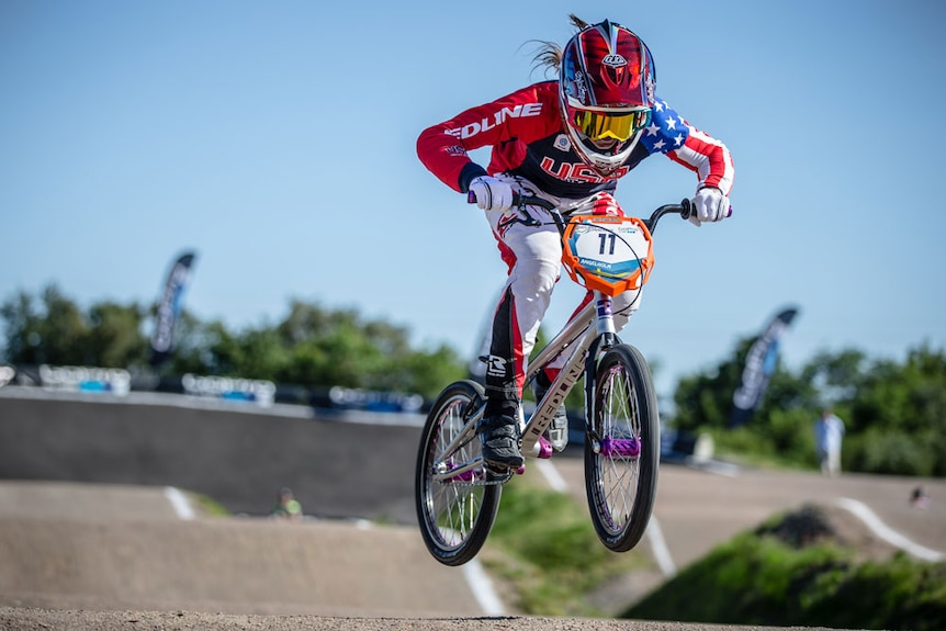 Alise rides her BMX over a jump