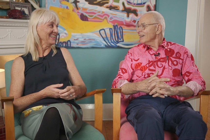 Dr Mary Dobbie and Dr Karl sit side by side, smiling at each other.