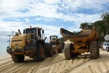 Two big earth-moving vehicles stand on Qld's Moreton Island during the clean-up effort after a massi