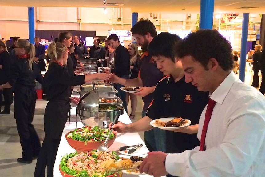 Delegates at a conference serving themselves from a long table of food