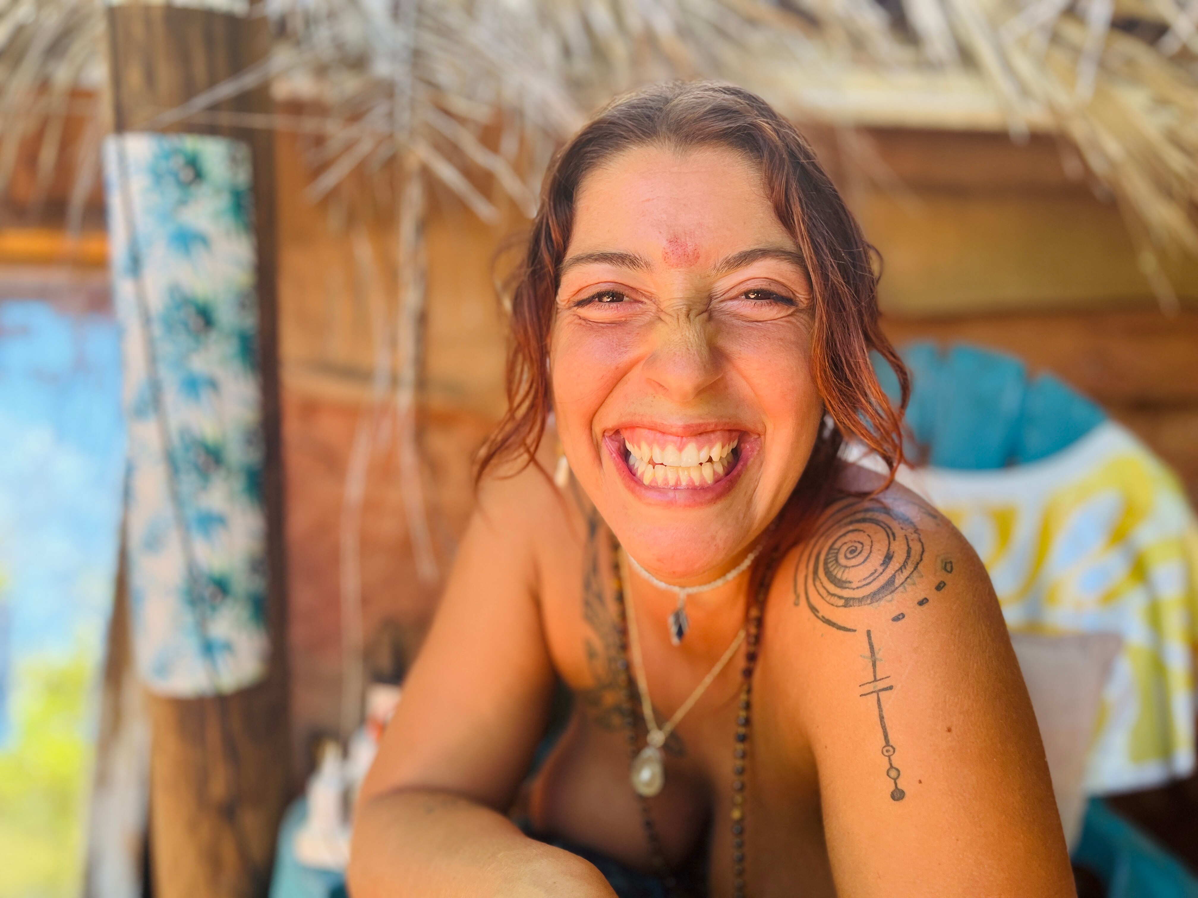 A woman with brown hair and tattoos smiles broadly