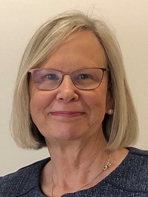 A woman with short blonde hair and glasses. 