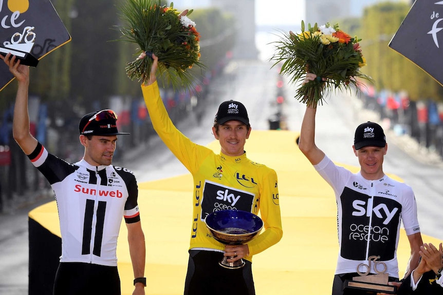 Geraint Thomas, in yellow, stands between Tom Dumoulin and Chris Froome with all holding a bunch of flowers in the air