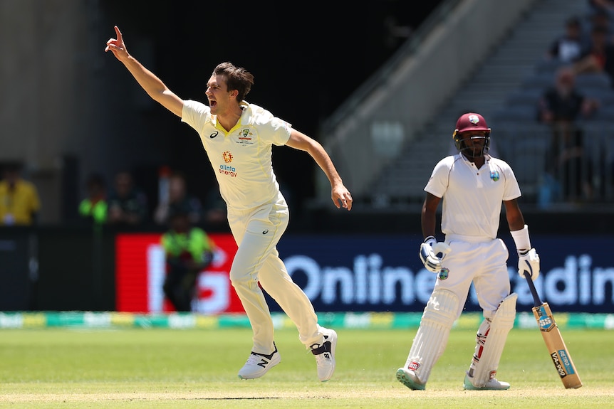 Australia bowler Pat Cummins runs away and points to the sky in celebration after a wicket in a Test against West Indies.