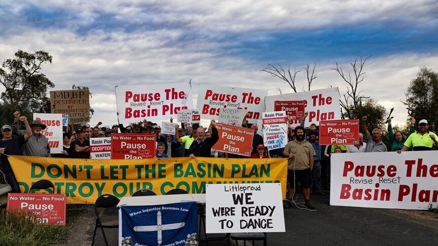 Protesters hold signs calling for a pause to the Murray Darling Basin Plan
