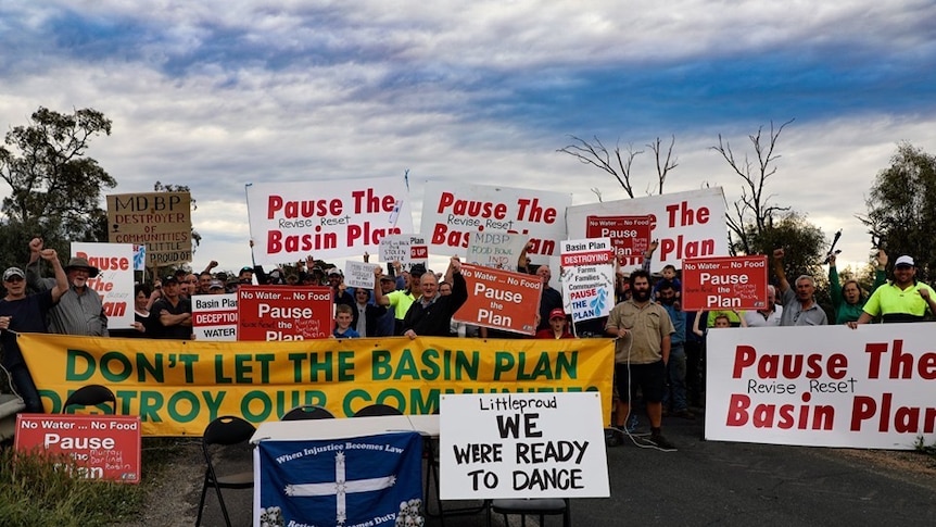 Protesters hold signs calling for a pause to the Murray Darling Basin Plan