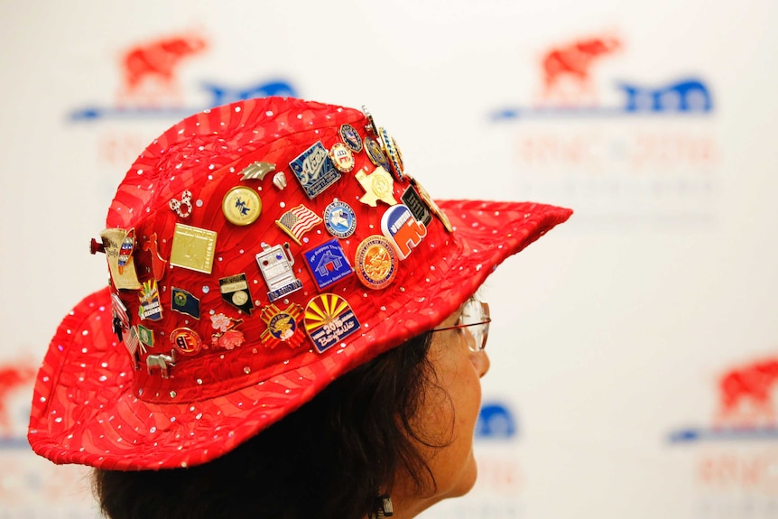 A Republican delegate wears a hat covered in buttons.