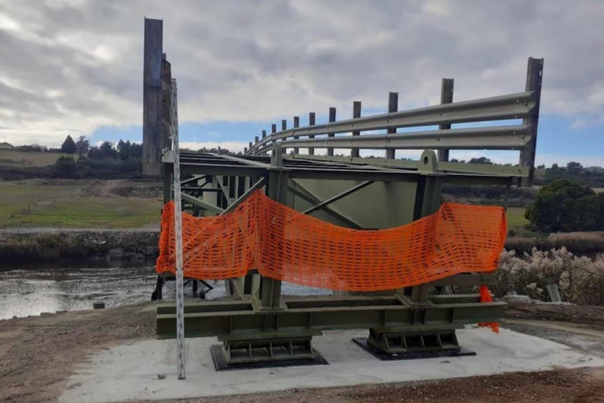 Orange temporary fencing is draped over the steel girders that make up an abutment of a bridge.