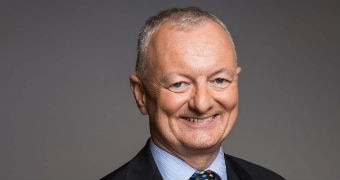 ABC election expert Antony Green smiles at the camera with his hands clasped behind his back.