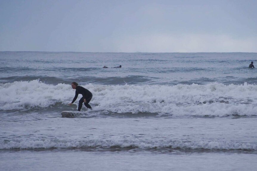 Beginner surfer Jacinta Henriksen surfing on a cold grey day in Victoria