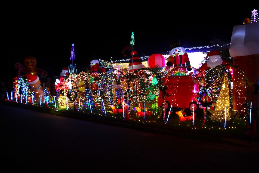 Hundreds of lights and inflatables in front of a house at night.