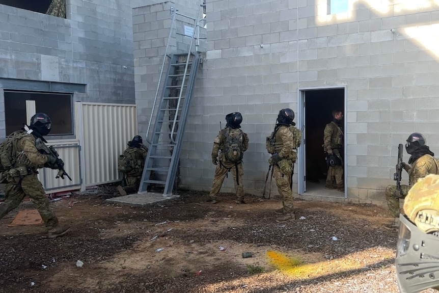 Soldiers in uniform next to brick building