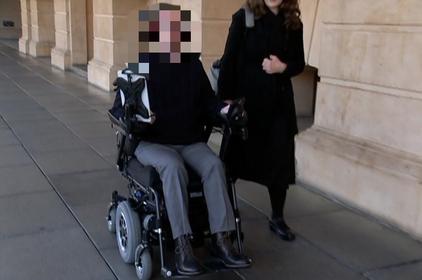 A man in a wheelchair with a pixelated face next to a woman