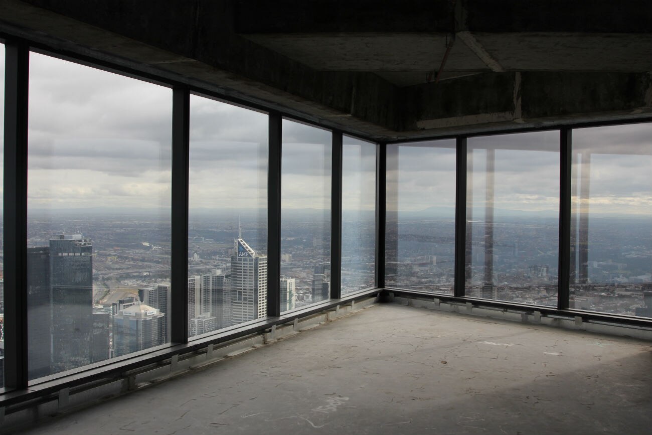 An empty apartment with windows looking out over the city to the horizon.