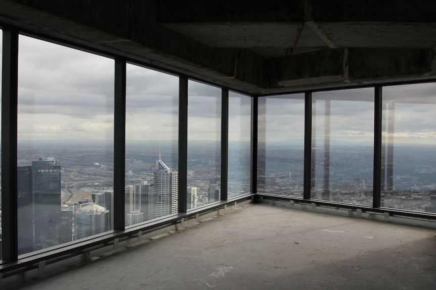 An empty apartment with windows looking out over the city to the horizon.