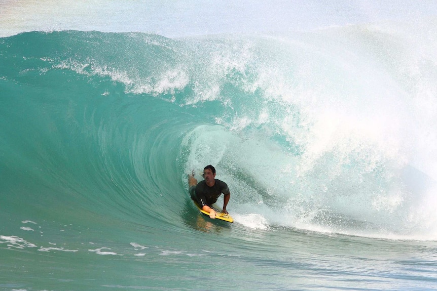 A bodyboarder rides a thick tube.