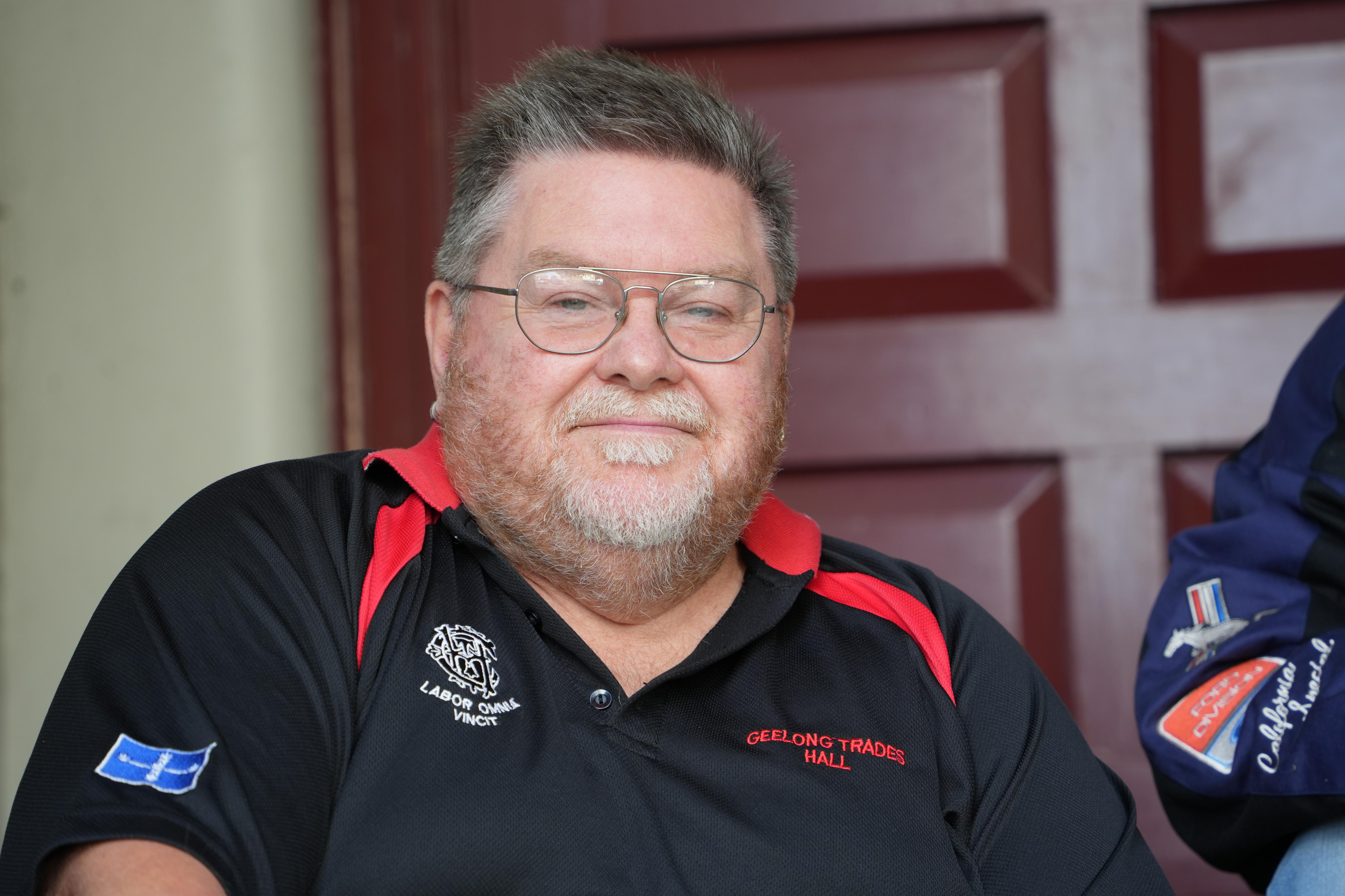 A man (Anthony Anderson) with glasses wearing glasses and a red and black polo shirt.