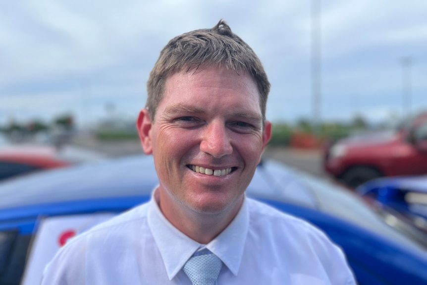 A headshot of a smiling middle aged man with brown hair 