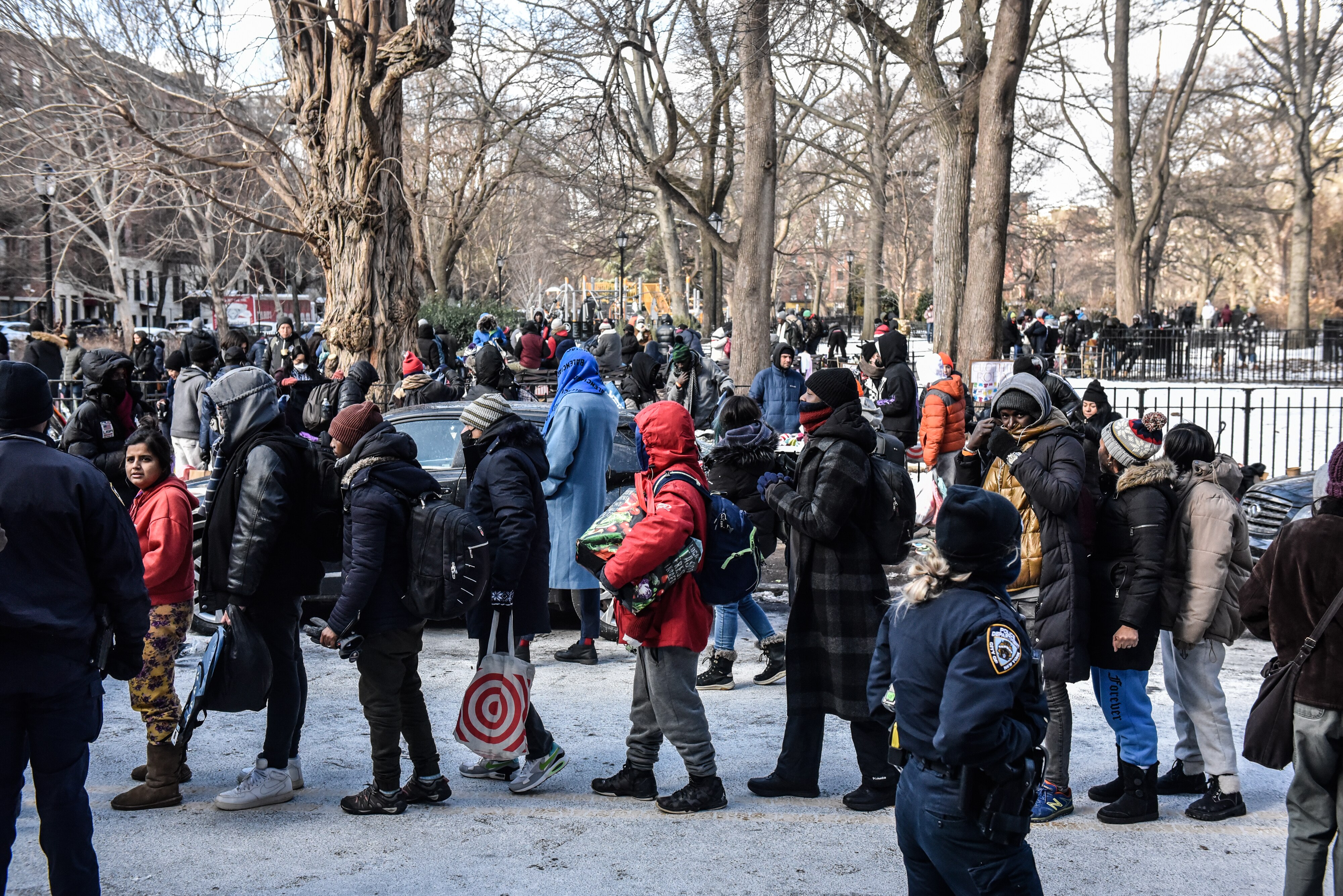 People line up in the snow for food and clothing.