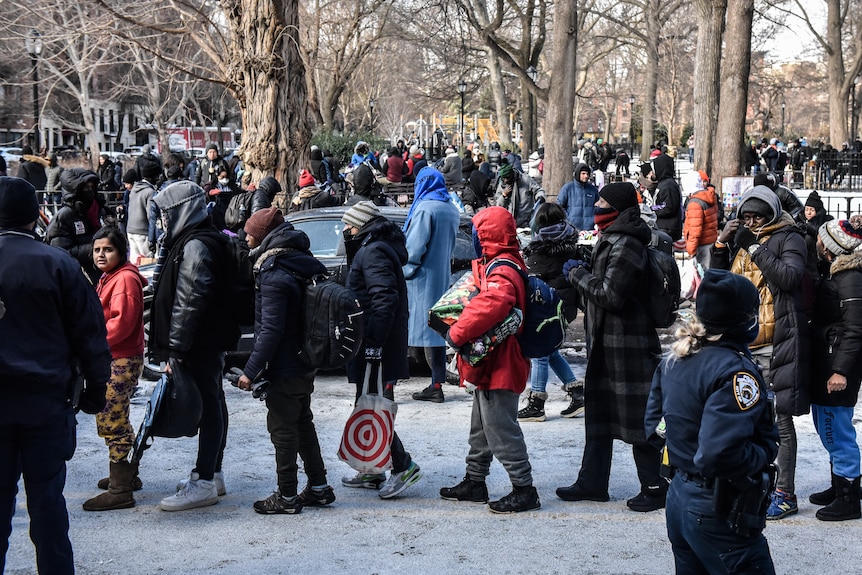 People line up in the snow for food and clothing.