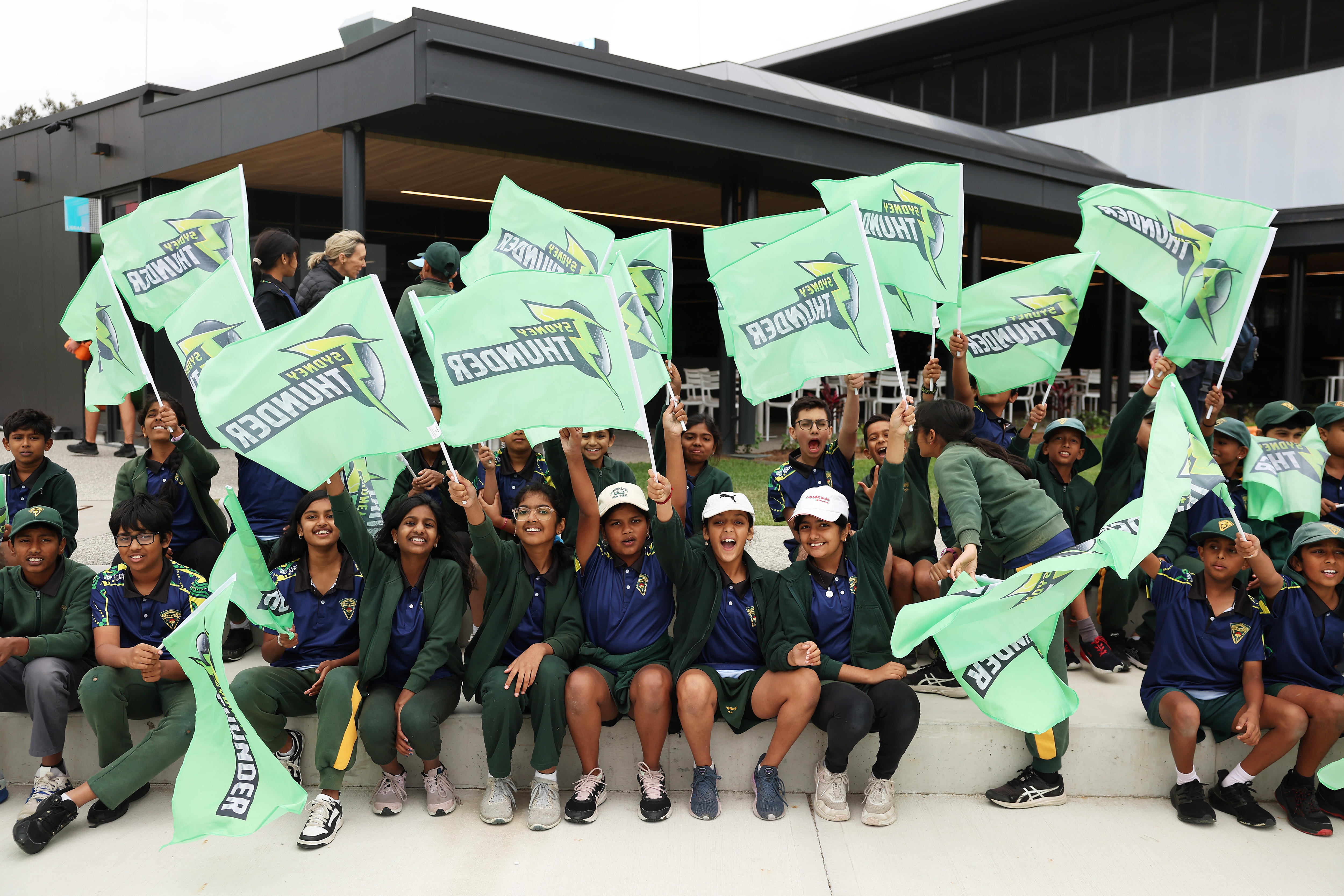 Young cricket fans waving Sydney Thunder flags.