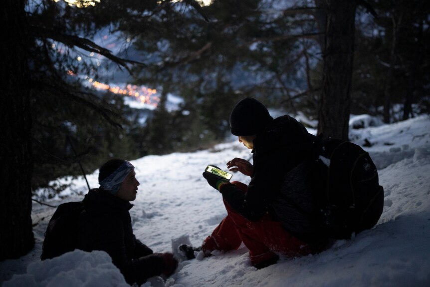 Two men checking a map on a phone in the Alps.