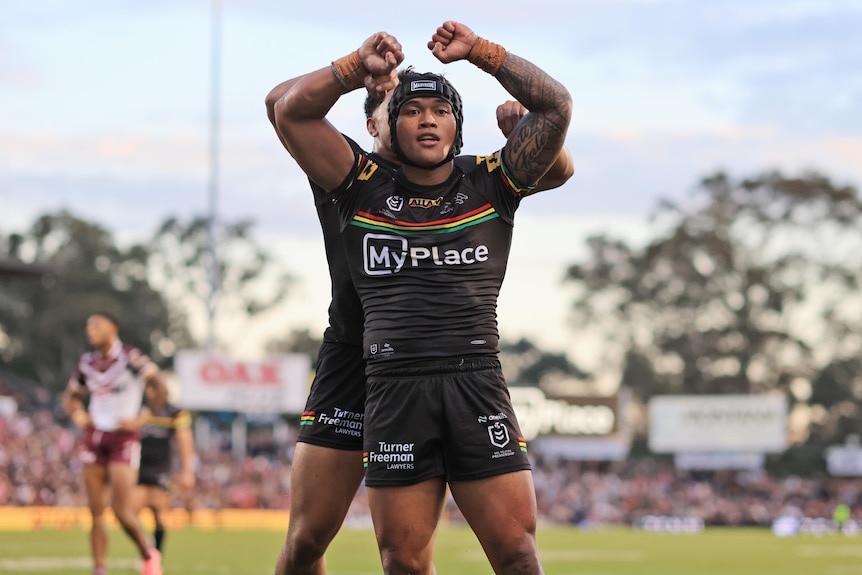 NRL player Brian To'o of the Panthers celebrates a try but raising his arms above his head, flexing his biceps