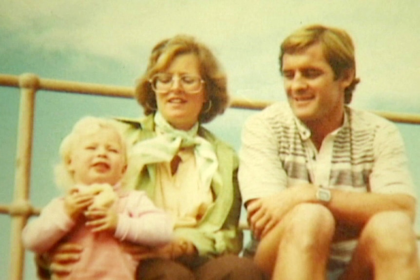 an old photo of a woman sitting down holding onto a toddler next to a man