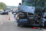 The front half of a car is pictured wedged under a bus, with the back half seen in the distance, at a crash site in Darwin.