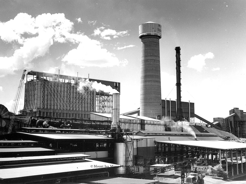 A wide shot shows a large tower in an industrial setting with smoke surrounding the area