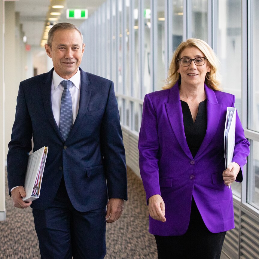 WA Premier Roger Cook and Rita Saffioti walk down a long corridor.
