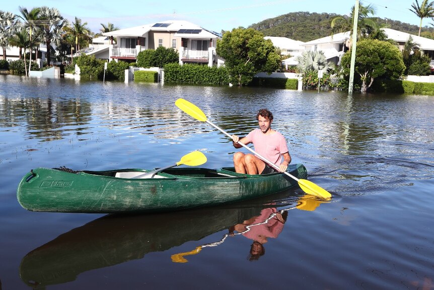 A man in a canoe on a flooded street